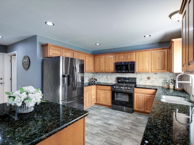 kitchen with gas stove, stainless steel fridge, backsplash, and a sink