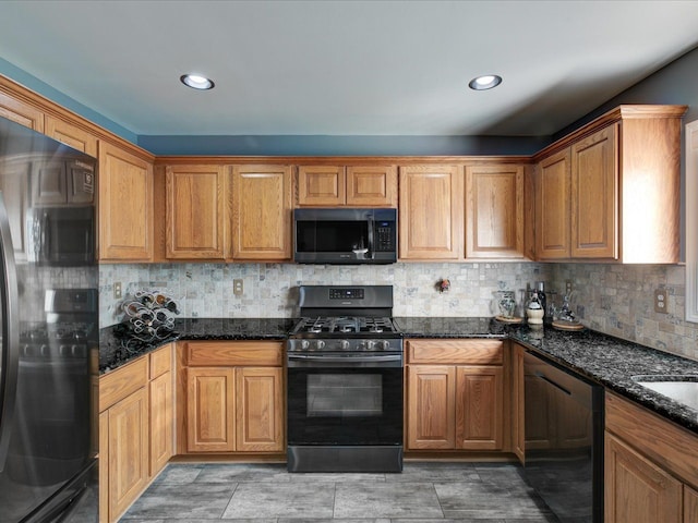 kitchen featuring tasteful backsplash, black appliances, brown cabinetry, and dark stone counters