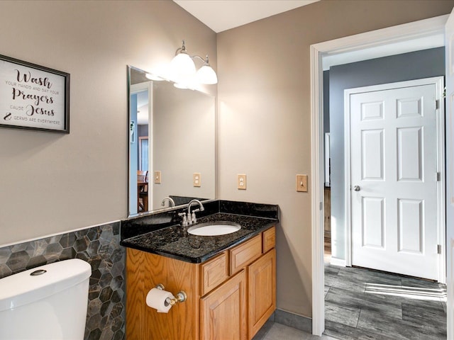 half bathroom featuring vanity, tile walls, and toilet