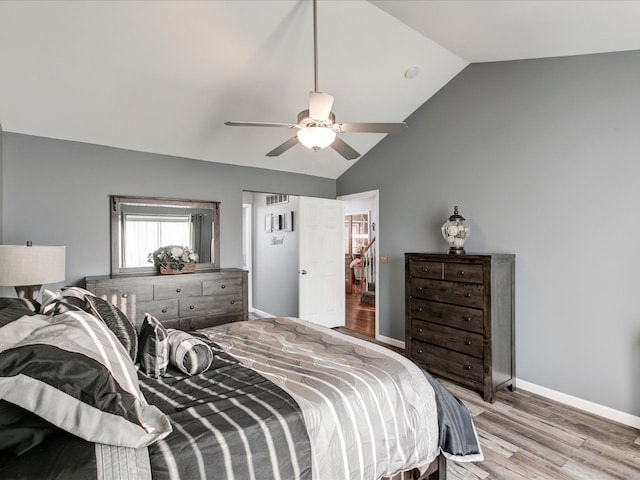 bedroom with wood finished floors, visible vents, baseboards, lofted ceiling, and ceiling fan