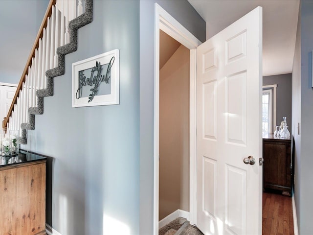 corridor featuring stairway, wood finished floors, and baseboards