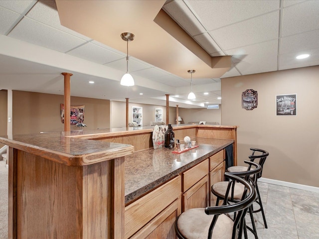 bar with recessed lighting, baseboards, indoor wet bar, a paneled ceiling, and hanging light fixtures