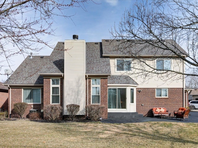 rear view of house featuring a shingled roof, a yard, brick siding, and a chimney