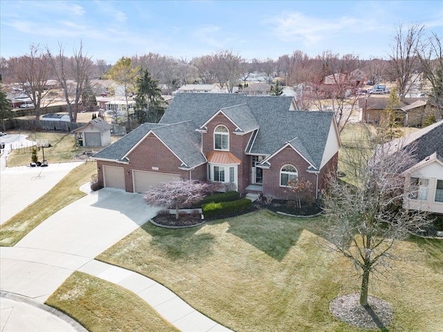 view of front of house featuring a front yard, an attached garage, a shingled roof, concrete driveway, and brick siding