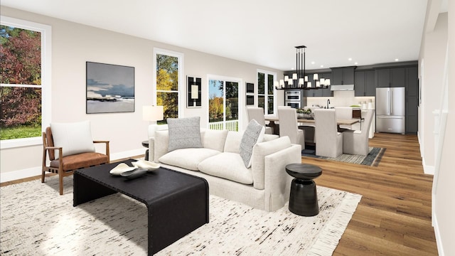 living room with a notable chandelier, recessed lighting, light wood-type flooring, and baseboards