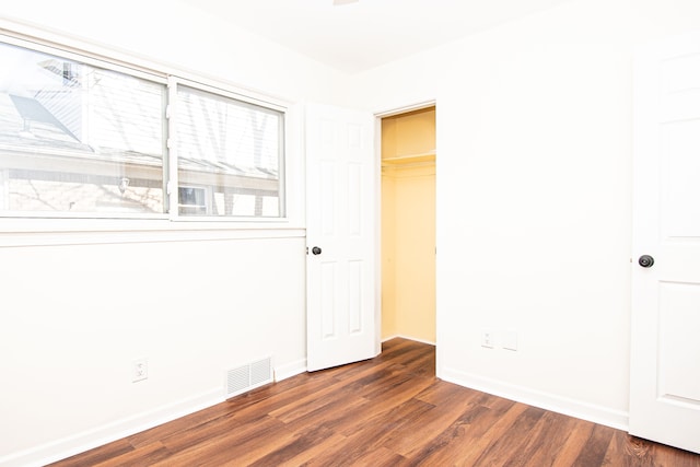 unfurnished bedroom with dark wood-style floors, visible vents, a closet, and baseboards