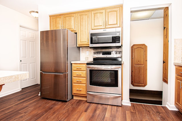 kitchen with dark wood-type flooring, backsplash, stainless steel appliances, light countertops, and baseboards