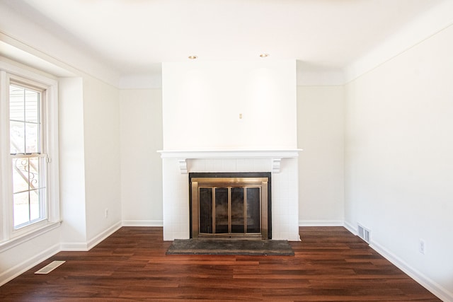 unfurnished living room featuring wood finished floors, visible vents, and a tile fireplace