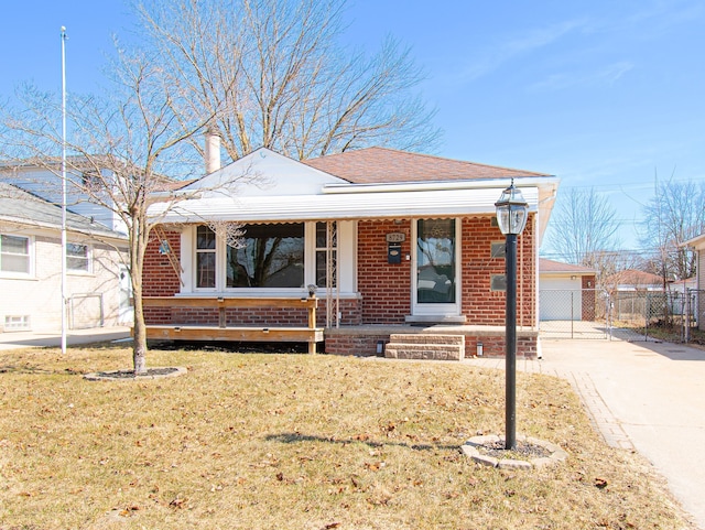 view of front of home with a front lawn, fence, brick siding, and covered porch