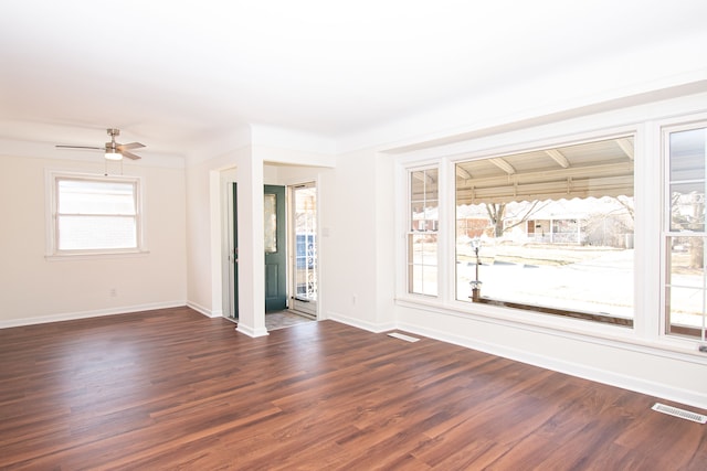 spare room featuring visible vents, baseboards, dark wood-style floors, and a ceiling fan