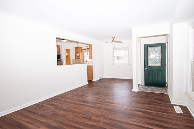 foyer entrance featuring dark wood-type flooring, a ceiling fan, visible vents, and baseboards