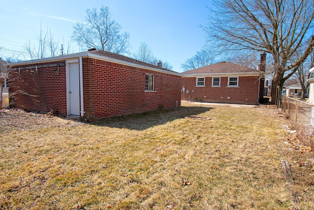 back of house featuring brick siding, fence, and a lawn