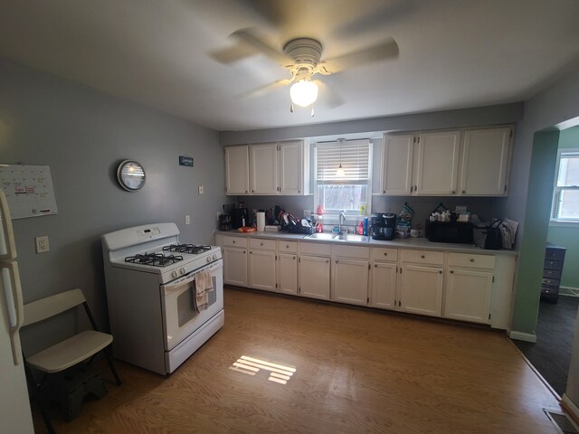 kitchen with a sink, white appliances, a healthy amount of sunlight, and ceiling fan