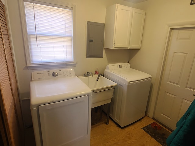 washroom featuring light wood-style flooring, electric panel, separate washer and dryer, cabinet space, and a sink