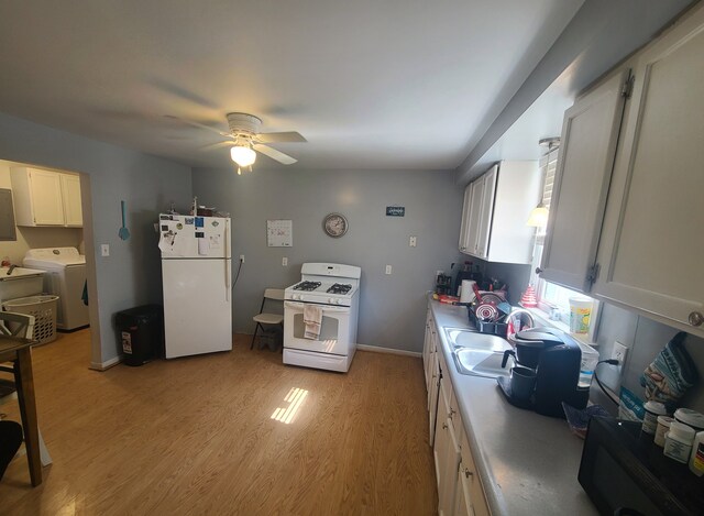 kitchen featuring white appliances, a ceiling fan, light wood-style flooring, washer / clothes dryer, and a sink