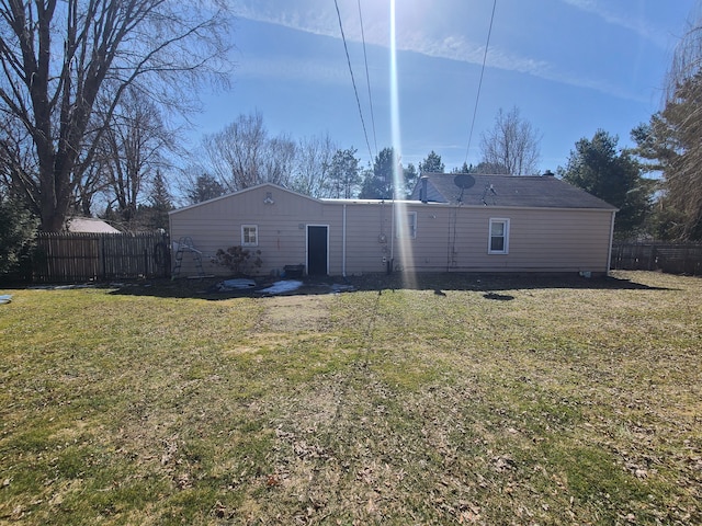 rear view of property with a lawn and fence