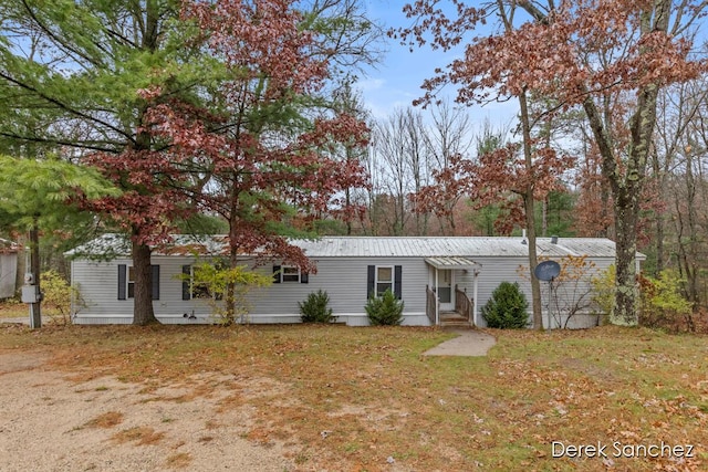 manufactured / mobile home featuring metal roof and a front lawn