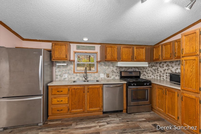 kitchen featuring a sink, appliances with stainless steel finishes, brown cabinetry, and light countertops