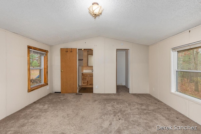 unfurnished bedroom featuring a textured ceiling, lofted ceiling, and carpet floors