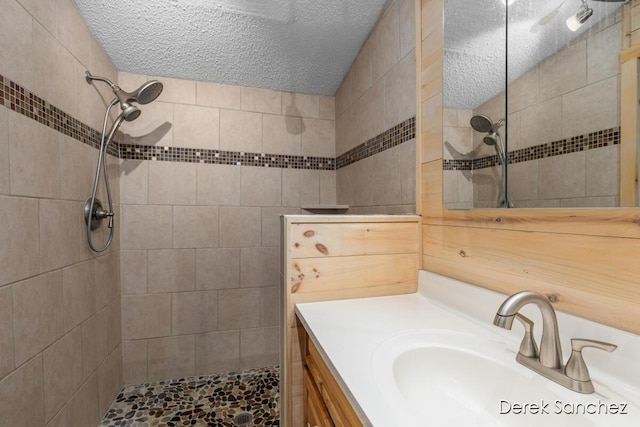 bathroom featuring a tile shower, a textured ceiling, and vanity