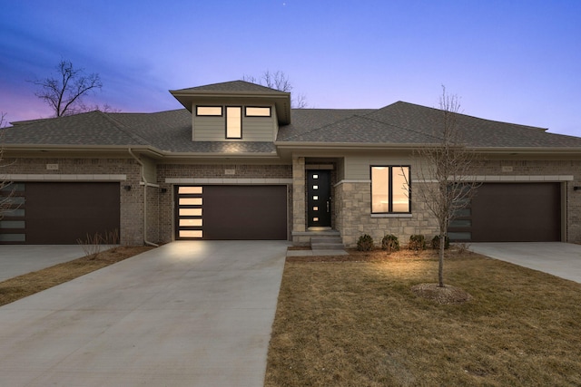 prairie-style house with brick siding, roof with shingles, and concrete driveway