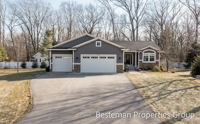 craftsman-style house with a garage, stone siding, and driveway