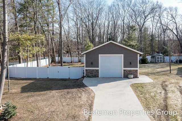 detached garage featuring a gate, driveway, and fence