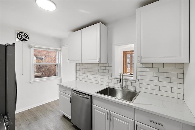 kitchen with visible vents, white cabinetry, freestanding refrigerator, a sink, and stainless steel dishwasher