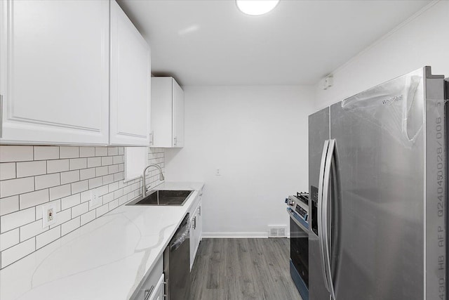 kitchen featuring a sink, light stone counters, decorative backsplash, stainless steel appliances, and dark wood-style flooring