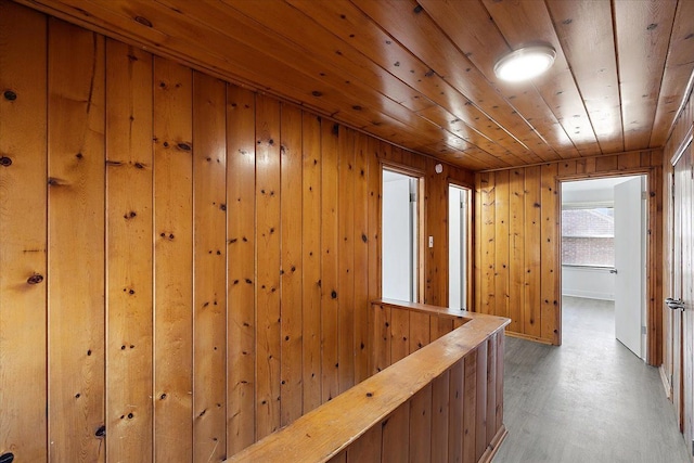 hallway featuring wooden walls, wood ceiling, and light wood finished floors