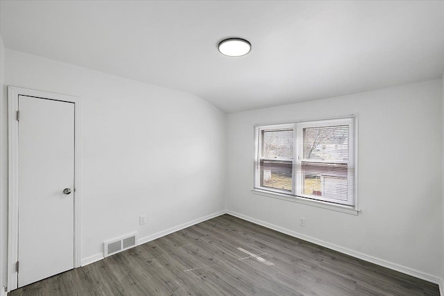 unfurnished room featuring visible vents, baseboards, wood finished floors, and vaulted ceiling