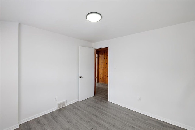 unfurnished room featuring visible vents, baseboards, and wood finished floors