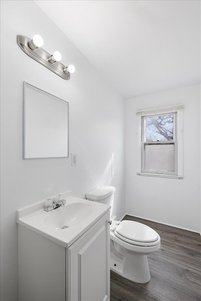 half bath featuring toilet, wood finished floors, and vanity