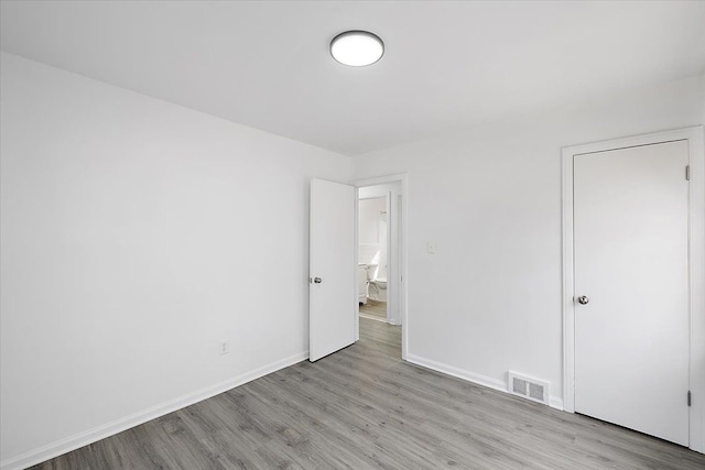 unfurnished bedroom with visible vents, baseboards, and wood finished floors