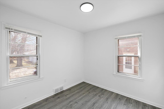 empty room with visible vents, baseboards, and wood finished floors