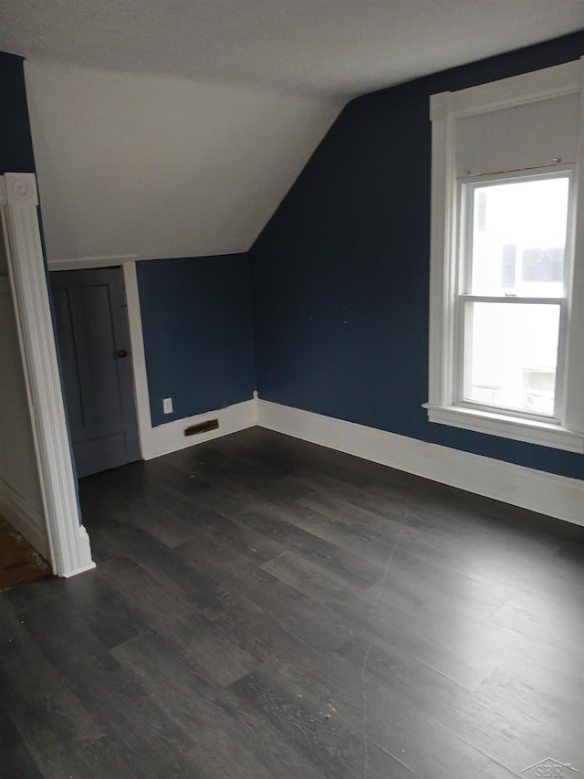 bonus room featuring vaulted ceiling, baseboards, and dark wood-style flooring