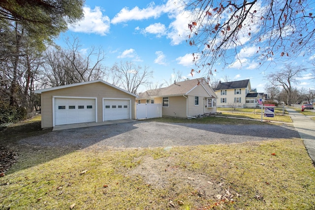 view of side of property with a detached garage, an outbuilding, and fence