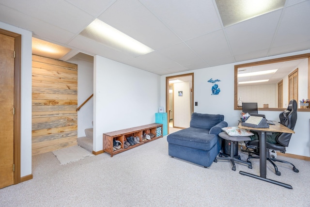 interior space featuring wooden walls, carpet, baseboards, and a drop ceiling