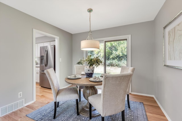 dining space with baseboards, visible vents, and light wood-type flooring