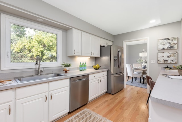 kitchen with light countertops, white cabinets, appliances with stainless steel finishes, and a sink