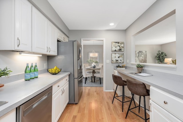 kitchen with recessed lighting, light countertops, white cabinets, appliances with stainless steel finishes, and light wood-type flooring