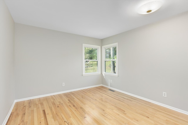 spare room with baseboards, visible vents, and light wood finished floors