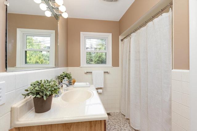 full bathroom featuring vanity, an inviting chandelier, wainscoting, curtained shower, and tile walls