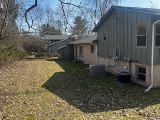 view of side of property featuring a yard, central AC unit, and board and batten siding