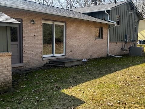 view of side of property featuring brick siding, a yard, cooling unit, and board and batten siding