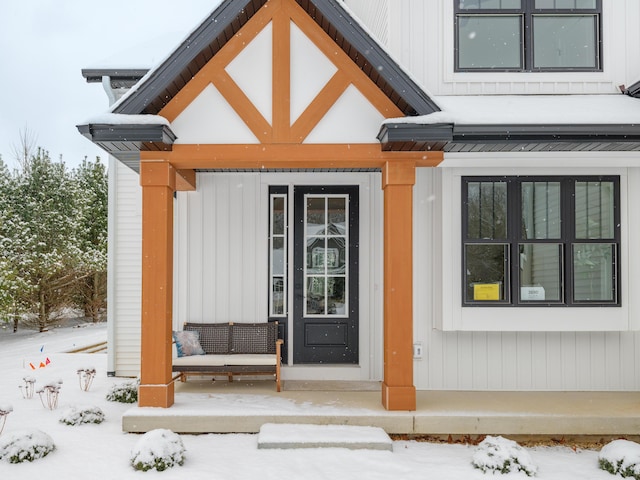 snow covered property entrance with a porch