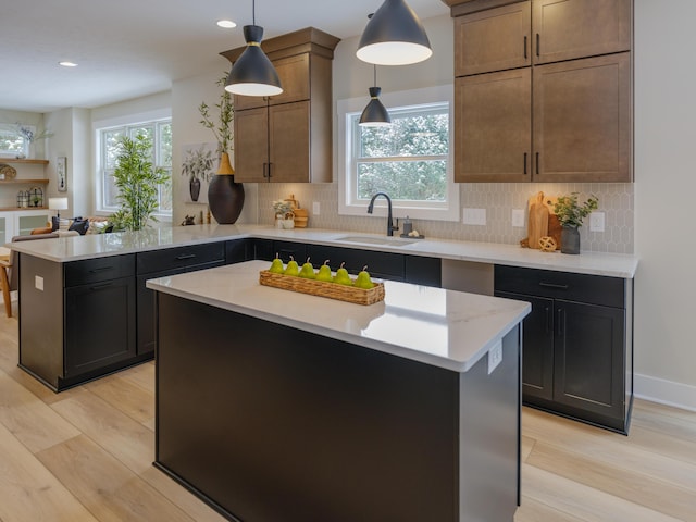 kitchen with decorative backsplash, light wood-style flooring, a peninsula, and a sink