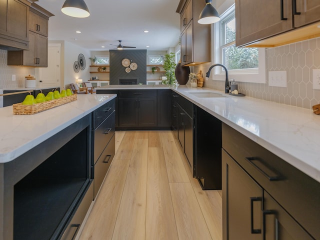 kitchen with a sink, light stone counters, tasteful backsplash, light wood-style floors, and ceiling fan