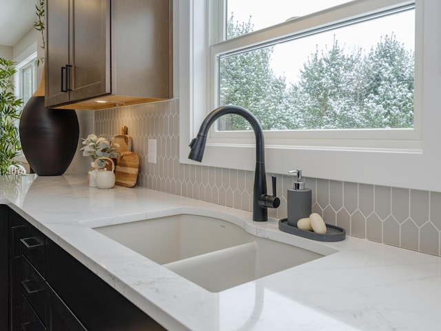 room details featuring light stone countertops, backsplash, and a sink