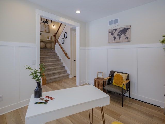 office area featuring visible vents, wainscoting, a decorative wall, and light wood-style floors